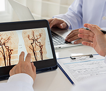 Arzt wertet Aufnahme von Blutgefäßen im Gehirn auf einem Tablet aus (c) shutterstock create jobs 51